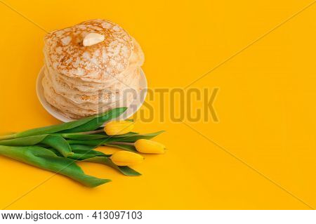 Staple Of Yeast Pancakes With Butter And Bouquet Of Tulips. Spring Holiday Traditional Russian Panca