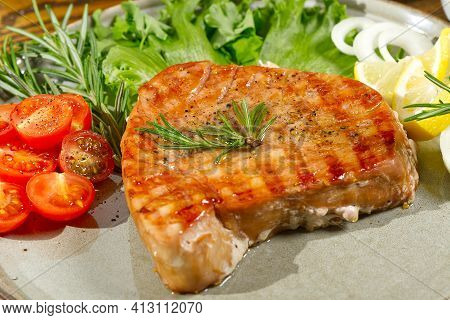 Tuna Steak Cooked On The Electric Grill. Tunafish Served On A Plate With Fresh Herbs And Vegetables.