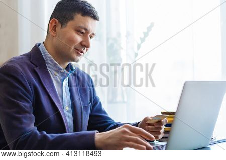 Millennial Man Businessman Holding Credit Bank Card And Using Laptop. Online Payment, Purchase, Shop