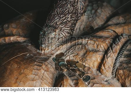 Old Coins Lie On A Wooden Carved Figure
