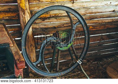 Steel Old Rusty Wheel From Agricultural Machinery Near Wooden Wall