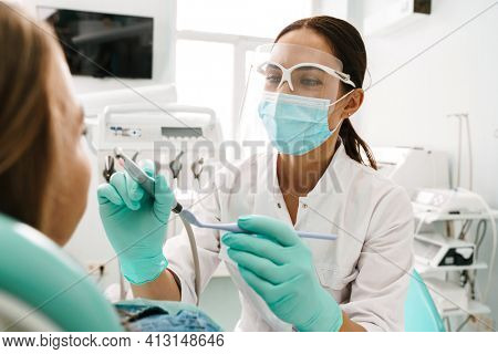 European mid dentist woman in face mask working in dental clinic