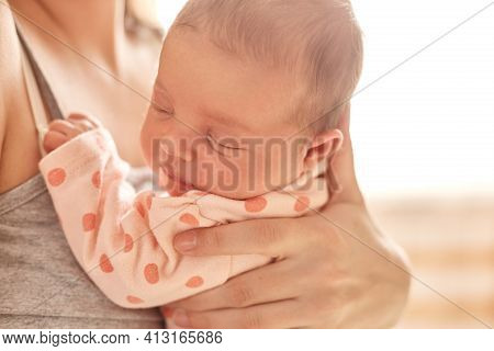 Newborn Baby On Mothers Arm, Sleepy Infant Wearing Sleeper With Polka Dots, Kid With Closed Eyes, Un