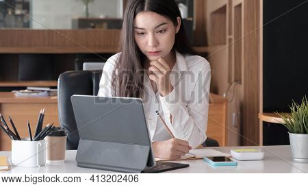 Photo Of Cheerful Joyful Asian Woman Writing Down Notes Holding Tablet For Data Analysis