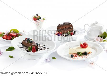 Dessert Table - created with Chocolate Cake, Classic Cheesecake, Ice Cream  and Chocolate Cheesecake. Fresh spring flowers on white table with berries and tea pot. Cake topped with berries and chocola