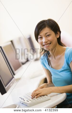 Frau sitzt im Computerraum eingeben und lächelnd