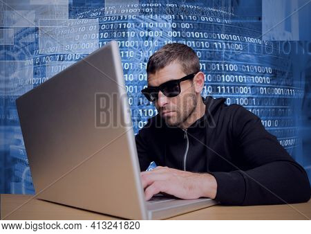 Composition of data processing and binary coding over hacker wearing sunglasses using laptop. online security and cyber attack concept digitally generated image.