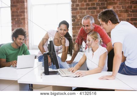 Cinco empresarios en oficinas mirando el ordenador y sonriendo