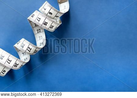 Centimeter Tape, Fitness And Weight Loss. Tailor's Meter, For Sewing, On A Blue Background. Meter, T