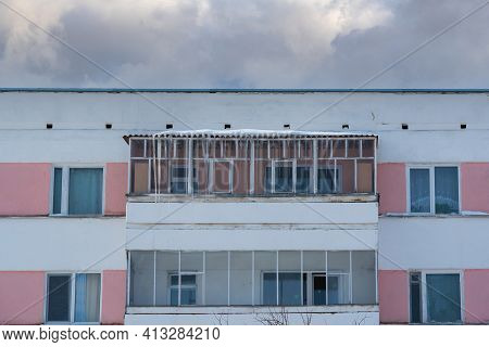 Agidel, Russia March 17.2021: Facade Of An Apartment Building With Huge Icicles On The Balcony