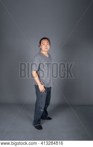 Asian Long Hair Friendly And Positive Man Is Posting And Standing In Front Of Gray Background With S