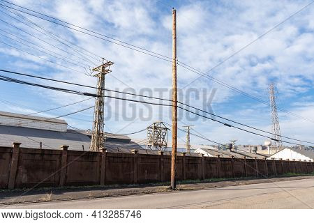 Long Wall Between Street And Industrial Steel Mill, Power Lines, Blue Sky With Clouds, Horizontal As