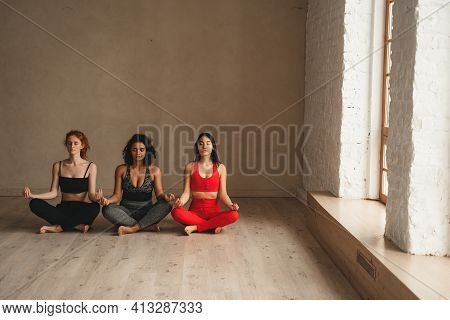 Fit Athletic Women Doing Meditation, Healthy Lifestyle. Beautiful Women Working Out In Gym Together.