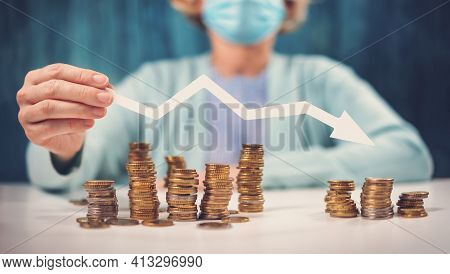 Woman Holding An Arrow Down Over Stack Of Coins. Contept Of Falling On The World Market In Pandemic 