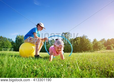 Children Are Playing On The Sport Field With Hula Hoop And Rubber Fitness Ball. Active Boy And Girl 