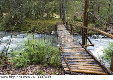Homemade Wooden Pedestrian Bridge Over A Fast Mountain River In A Deep Forest. River Stiavnica. Jans