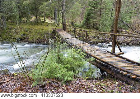 Homemade Wooden Pedestrian Bridge Over A Fast Mountain River In A Deep Forest. River Stiavnica. Jans