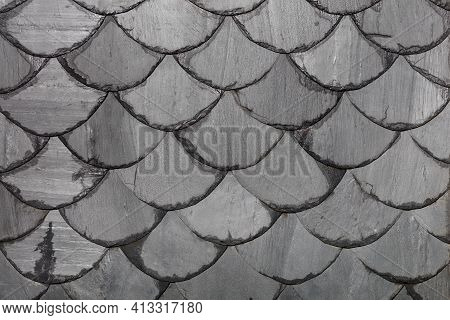 The Roof Is Made Of Gray Slate Slabs In The Shape Of Fish Scales. Background And Texture, Close-up.