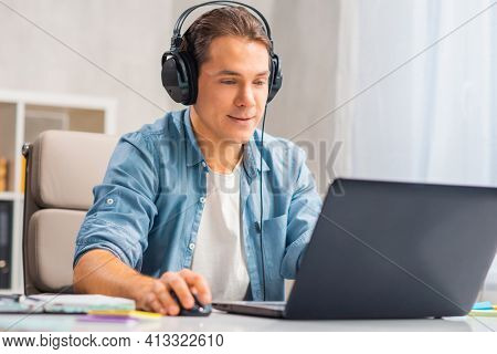 Workplace of freelance worker or sudent at home office. Young man works using computer and other devices. Remote job.