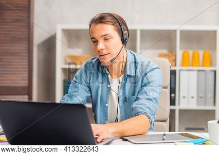 Workplace of freelance worker or sudent at home office. Young man works using computer and other devices. Remote job.