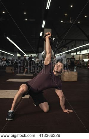 Vertical Shot Of A Handsome Muscular Male Athlete Doing Kettlebell Turkish Get Up