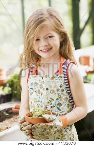 Jong meisje op broeikasgassen bedrijf ingegoten Plant glimlachen