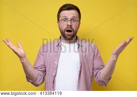 Shocked Man In Glasses And A Shirt Spreads Arms To The Sides And Looks In Bewilderment. Can Not Be. 