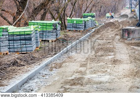 Paving Slabs In Stacks Are Located Along The Construction Site Of The City Park Walking Path. Laying