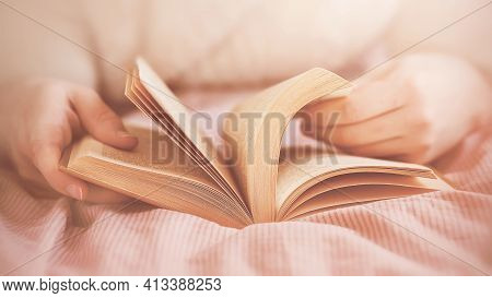 A Man In A White Sweater Is Lying On A Bed With A Pink Striped Blanket And Reading An Interesting Ol