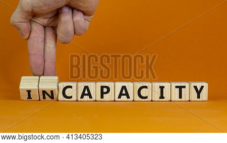 Capacity Or Incapacity Symbol. Businessman Turns Wooden Cubes And Changes The Word 'incapacity' To '