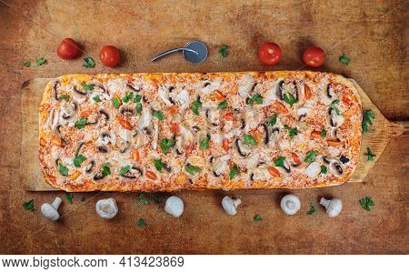 Long Pizza With Chiken And Mushrooms Lies On A Wooden Table. Roman Pizza On A Wooden Spatula. One Me