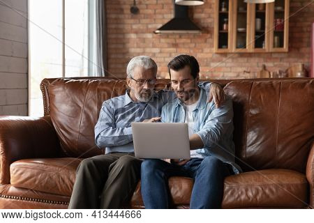 Grownup Son And Old Father Use Laptop At Home