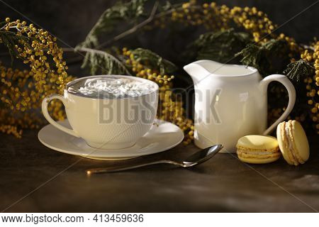 A Cup Of Coffee With Macaroons And Yellow Flowers