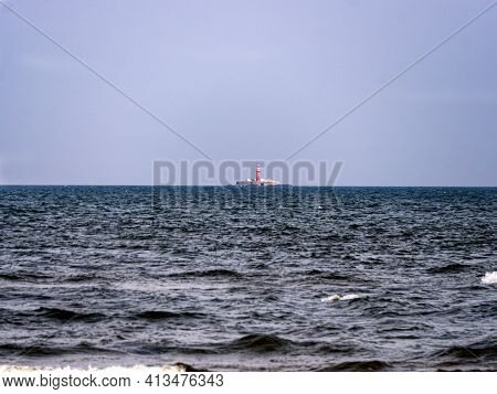 Far Out In The Sea Rises A Lighthouse Emitting Light For Ships.latvia, Cape Kolka, 22 September 2020