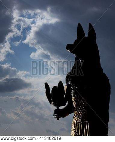 Still Life Of Statues Of Mythology Jackal Anubis Inpu Anup. In The Background Is A Blue Sky With Whi