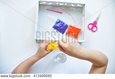 A Girl Girl Sprinkles Paraffin With A Spoon Makes Makes A Candle From Small Paraffin Granules. Kids 