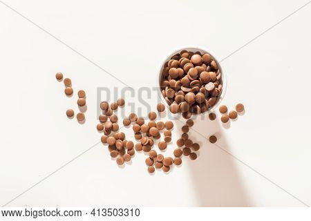 Chocolate Callets In A White Disposable Cup On A White Background. Top View Close-up. Flat Lay. Temp