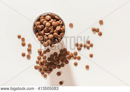 Chocolate In Callets In A White Disposable Cup On A White Background. Home-made Sweets. Top View Clo