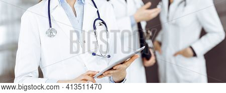 Unknown Woman Doctor Iusing Tablet Computer In Her Hands, While Standing In Clinic. Medicine Concept