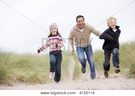 Far og to små børn kører på stranden smilende