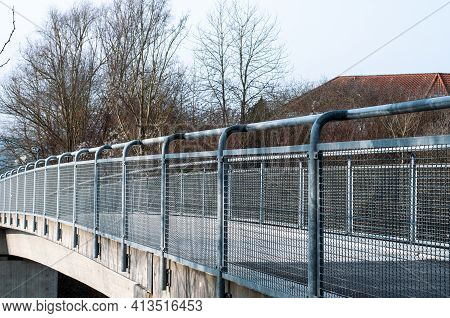 View Alongside The Metal Bannister Of A Pedestrian Bridge Over A Street In A City