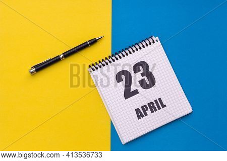 April 23th. Day Of 23 Month, Calendar Date. A Notebook With A Spiral And A Pen Lies On A Yellow-blue