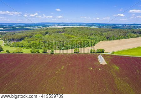 Red blooming crimson clover field (Trifolium incarnatum) and heap of bales seen from above