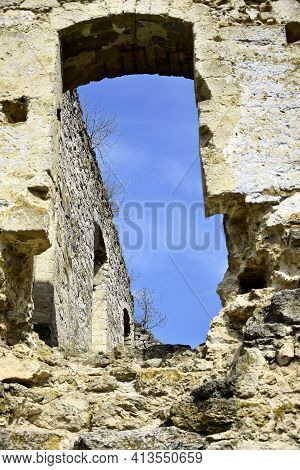 Ruins Of An Ancient Synagogue. View Of The Sky Through The Arch Window. Trees Growing On The Walls. 