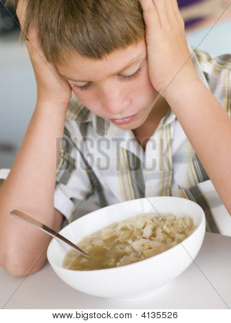 Giovane ragazzo In cucina a mangiare la minestra