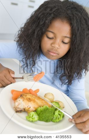 Giovane ragazza In cucina mangiare pollo e verdure