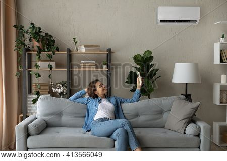 Smiling Woman Using Air Conditioner Remote Controller, Switching Temperature