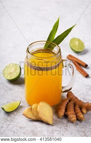 Healthy Drink From Turmeric And Ginger Roots And Lime In A Glass On White Concrete Background. Jamu 