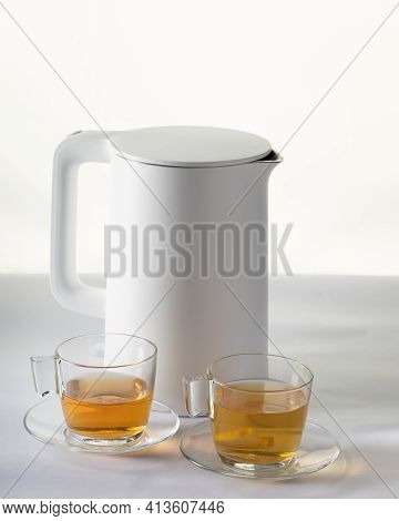 White Electric Kettle And Two Cups Of Hot Tea On Table