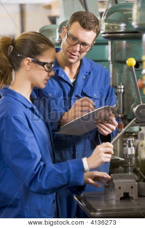 Two Machinists Working On Machine